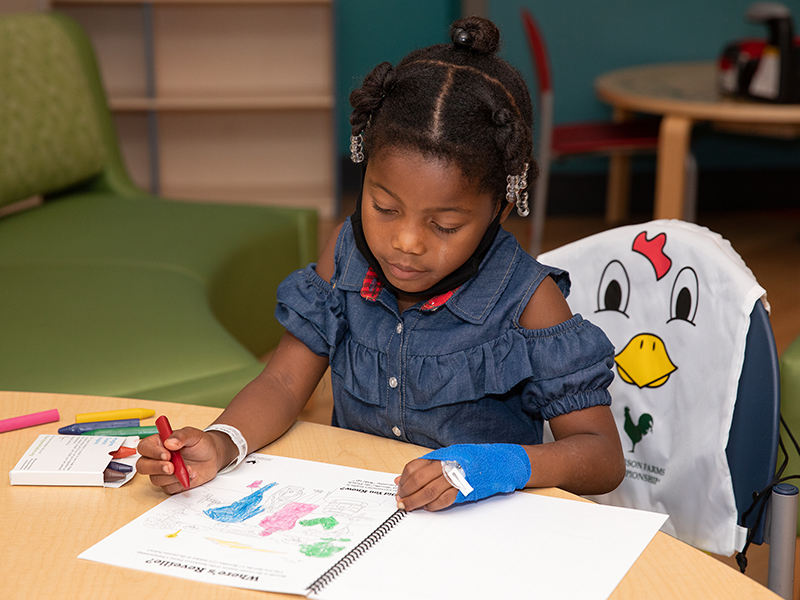 Jakia Jones of Vicksburg, a Children’s of Mississippi patient, colors a page in the Sanderson Farms Championship activity book included in the tournament backpack given to patients.